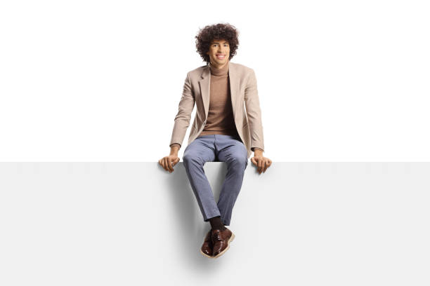 istock Smiling young man with curly hair sitting on a blank panel 1411205418
