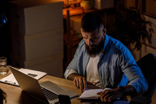 istock Hipster businessman working late at his desk, reading notes and brainstorming new ideas 1411205634