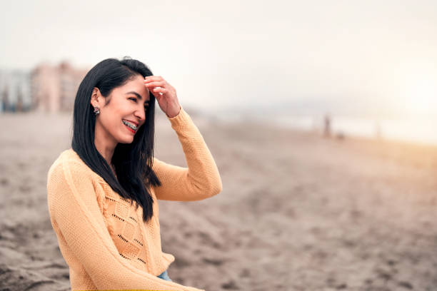 young latin woman with braces laughing on the beach portrait stock photo