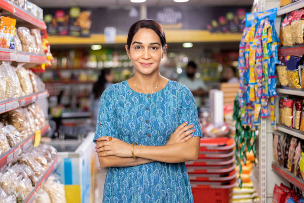 Portrait of Happy woman owner with arms crossed at shop Happy woman owner with arms crossed at grocery aisle of supermarket retail occupation stock pictures, royalty-free photos & images