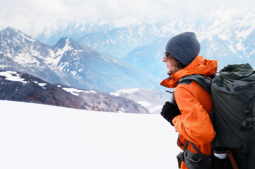 Man traveler with backpack hiking in winter mountains. Travel and outdoor activity concept
