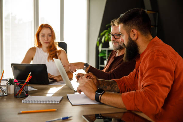 istock Businessman pointing at something on his laptop screen while co-working with his colleagues 1411207698