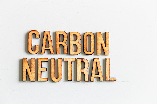Wooden letters spelling words 'Carbon Neutral' on white background. Room for copy space.