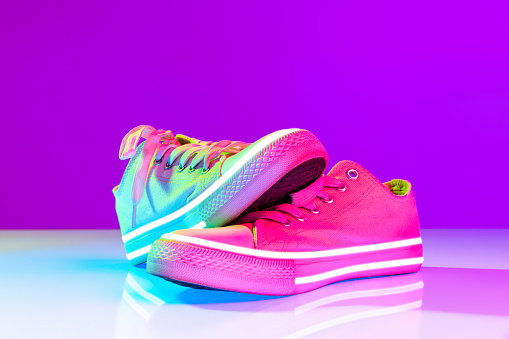 Image of fashionable sports shoes, sneakers isolated over colored neon background. Urban city fashion, fitness, sport, training concept. Copy space for ad, text, design. Mockup