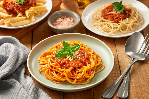 Plates of penne pasta and Spaghetti with bolognese sauce on wooden high angle view