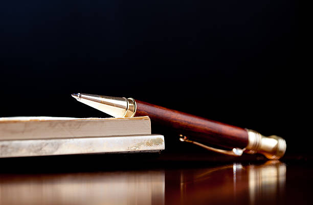 istock Elegant pen lying on a notebook with dark background 141120974