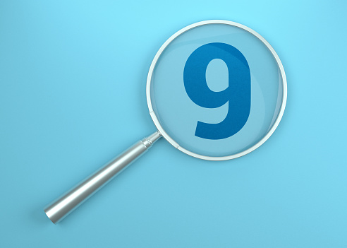 Metallic magnifying glass over number 9 on Blue background.