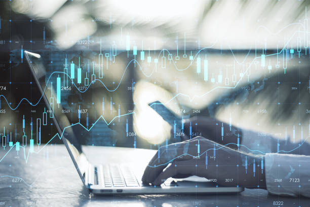istock Close up of businessman hands using smartphone and laptop on desktop with and creative glowing forex chart hologram and map on blurry background. Stock, market and invest concept. Double exposure. 1411210949