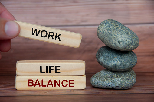 Work life balance text on wooden blocks with rocks and wooden cover background. New ways of working concept