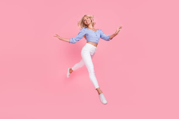 Full length photo of charming shiny girl dressed blue top jumping high walking isolated pink color background stock photo
