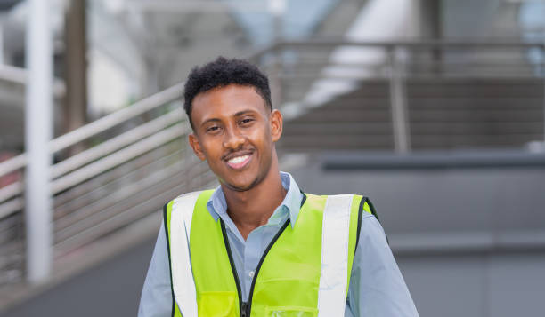 istock portrait of black engineer in glow shirt, smile, looking at camera while working at construction site outside building in city with copy space 1411213613