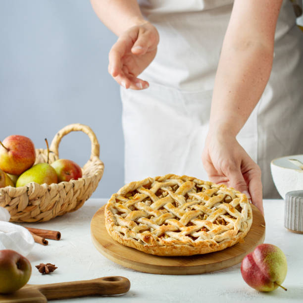 istock Female hands put a pear pie with  latticeon the table 1411214532