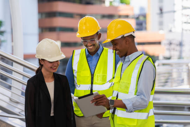 istock group of engineer team working together at construction site outside building in city. black businessman and caucasian businesswoman with helmet looking at tablet 1411214563