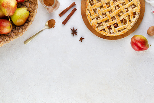 Textured white background with copy space with cinnamon pear tart with lattice, frame