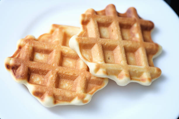 Two freshly baked Belgian waffles on white plate. Recipe dough for Belgian waffles concept