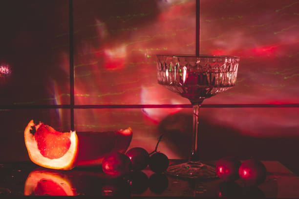 хрустальный бокал для коктейлей на стеклянной поверхности. фрукты – виноград, грейпфрут рядом со стаканом. абстрактный фон. - barware стоковые фото и изображения