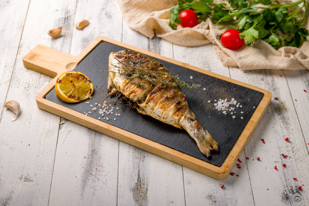 istock Dorado on grill on a black stone on white wooden table 1411217768