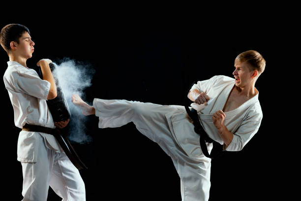 ritratto dinamico di combattenti maschi di karate-do in uniforme sportiva che si allenano insieme isolati su sfondo nero. concetto di sport, educazione, abilità, arti marziali, salute - extreme sports karate sport exercising foto e immagini stock