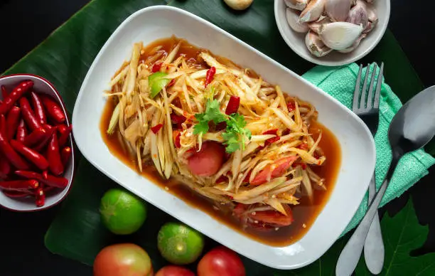 Thai Food Style-papaya salad spicy ''Som Tam Thai''in a white plate placed on a black table top view.