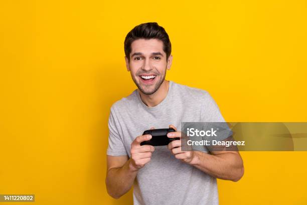 Photo Of Nice Brunet Millennial Guy Playstation Wear Grey Tshirt Isolated On Yellow Color Background Stock Photo - Download Image Now