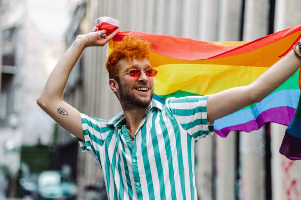 istock Young gay man holding rainbow flag and walking 1411223917