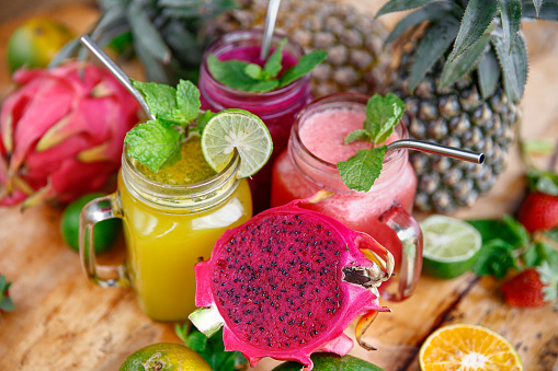 Close-up shot of variation fresh fruit juices placed around sliced organic fruits