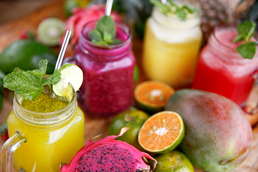 Close-up shot of variation fresh fruit juices placed around sliced organic fruits