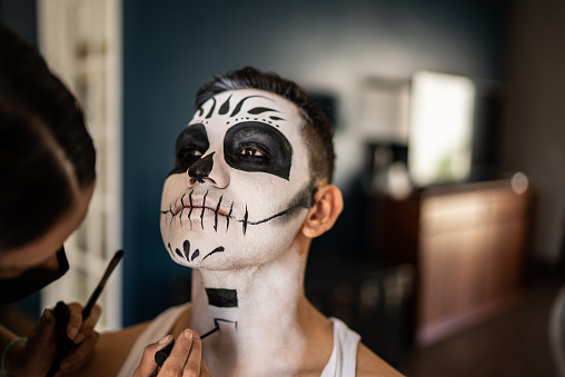 Young man having her makeup done for day of the dead