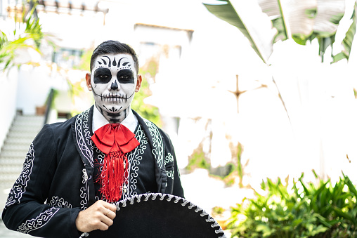 Portrait of a young man with makeup of day of the dead and traditional clothing