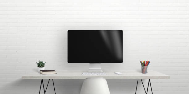 istock Computer monitor on work desk with brick wall in background. Blank screen for mockup, web design presentation. Work desk with books and pens 1411235216