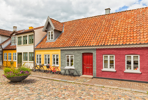 Idyllic cobbblestone alley with colorful small houses at the old town of Odense, capital of Funen, Denmark