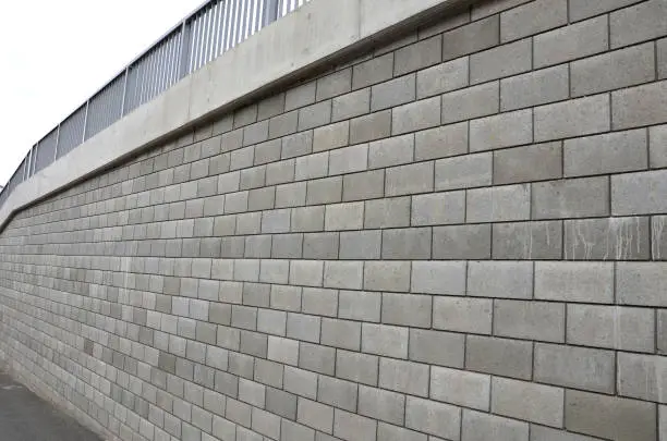 Photo of holding a road notch of a bridge forecourt tunnel. retaining wall with concrete grouting is covered with fake, optically prettier wall. fencing with hollow bricks filled with wires, railing,steel