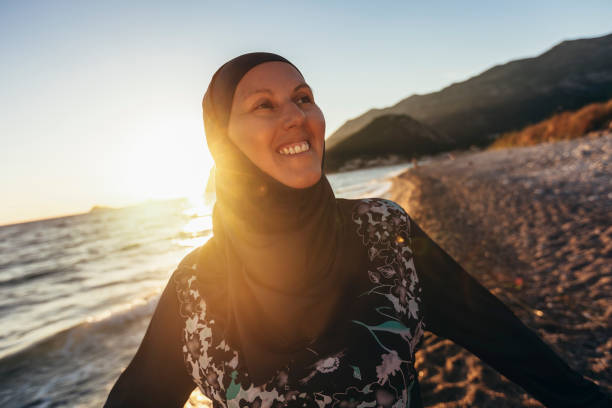 Woman in hijab posing on the beach with the sea in the background stock photo