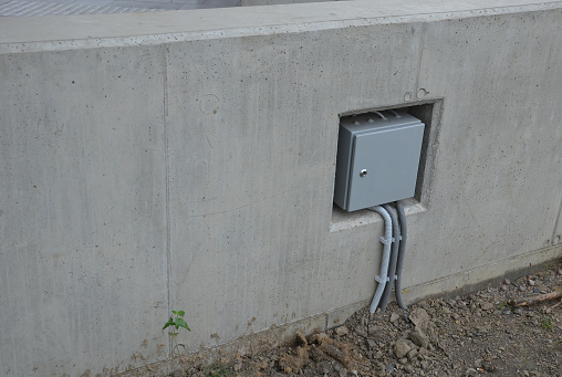 electrical switchboard on a concrete wall in a niche. felt box with a door and a patent lock to protect against entry. protecting pipes on a cable going underground