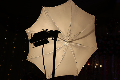 Flash diffuser setup using an umbrella and halogen tube lamp. Studio diffuser with white reflector umbrella