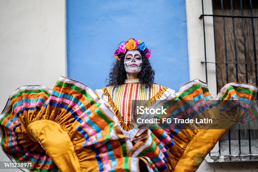 istock Portrait of a mid adult woman dancing and celebrating the day of the dead 1411238971