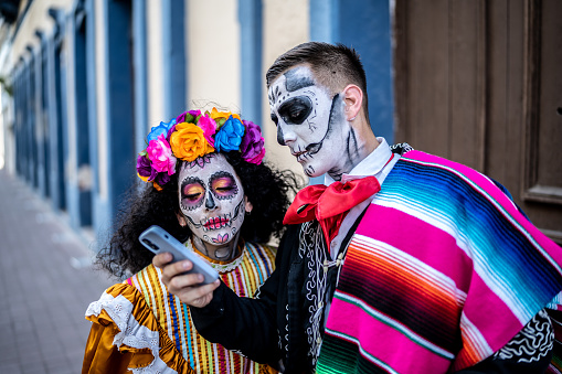 Couple using mobile phone on day of the dead at city