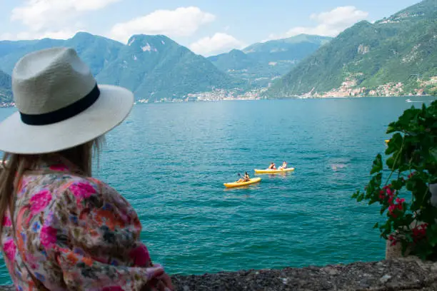 Photo of Female tourist watching kayakers in lake como from the Famous Villa del Balbinello Italy