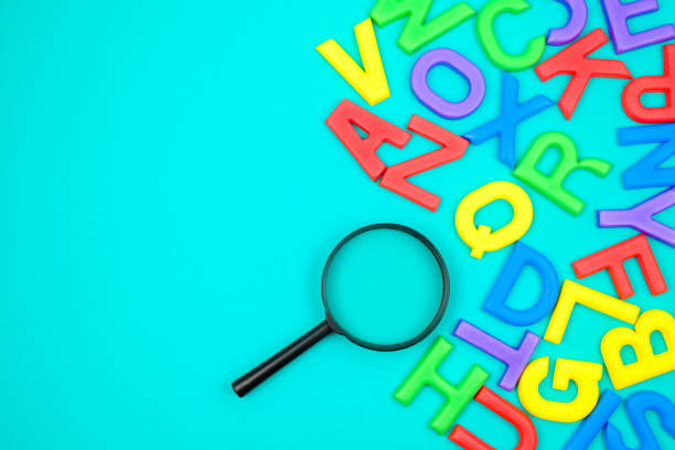 Scattered English alphabets with magnifying glass