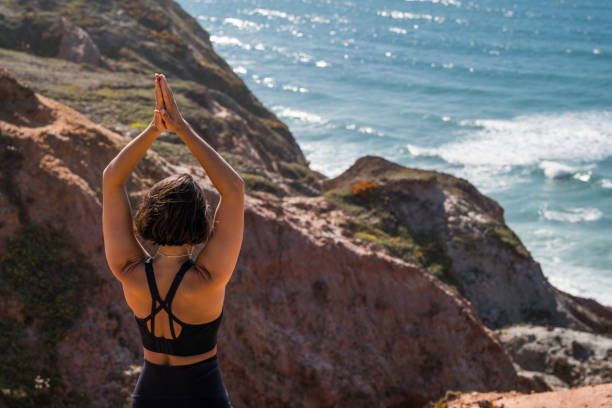 istock Woman making praying gesture while standing at the crag behind the ocean 1411241297