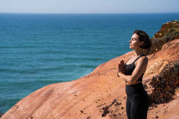 istock Peaceful woman making hands at prayer gesture while meditating at the sandy beach 1411241298