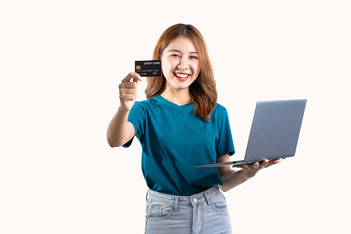 Cute Asian woman holding credit card and laptop computer isolated on white background.