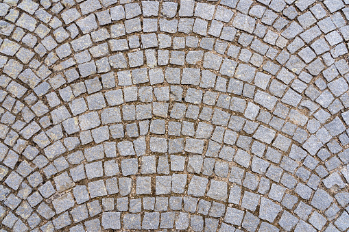 Granite cobblestone pavement background. Full frame of cobbles in arched rows. Natural stone textured background