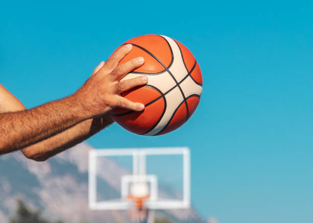 青い空晴れた夏の日の背景にそれを渡す準備ができているスポーツバスケットボールボールを持っている大人の男性の手 - men summer passing tossing ストックフォトと画像