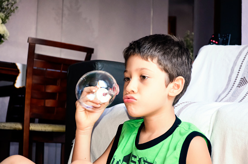 Portrait of a child blowing soap bubbles. Salvador, Bahia, Brazil.