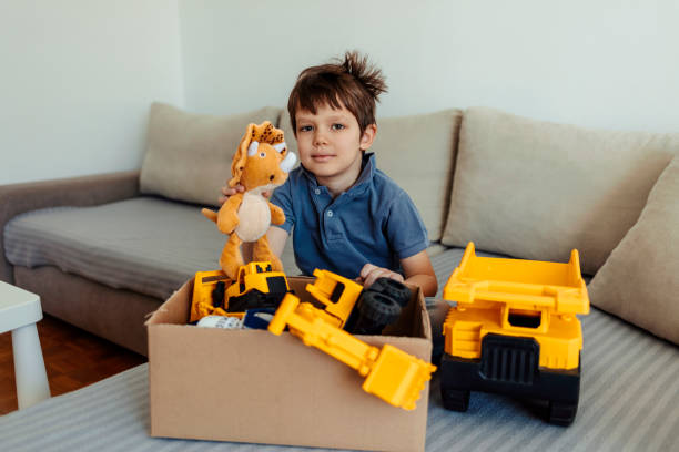 istock Donation concept. Boys hands holding donate box with toys and some clothes. Copy space. 1411245954