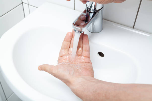 istock Man washes his hands in a white sink close-up 1411247209