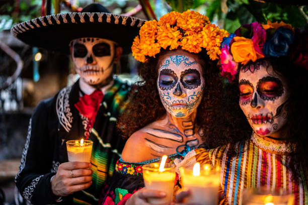 Friends celebrating the day of the dead lighting candle stock photo