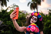 Mid adult woman doing a selfie and celebrating the day of the dead