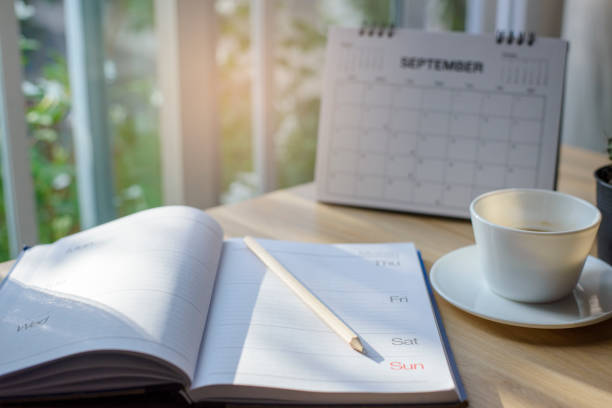 istock Diary, Calendar and agenda for Event Planner to plan timetable, appointment, organization, management on office table. Desktop Calender and coffee place on wooden desk. Calendar Background Concept 1411250759